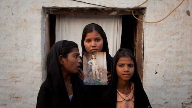 FILE PHOTO: The daughters of Pakistani Christian woman Asia Bibi pose with an image of their mother while standing outside their residence in Sheikhupura Pakistan 