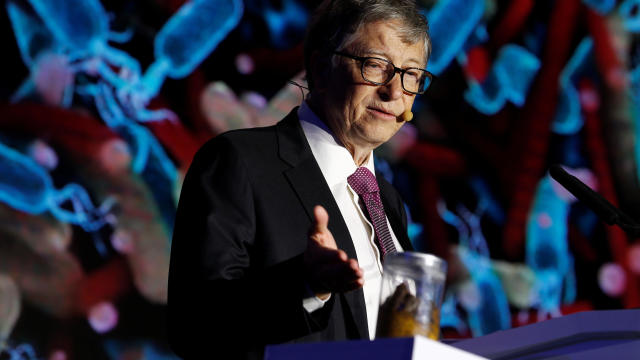 Microsoft founder Bill Gates points at a jar containing human faeces during his speech at the Reinvented Toilet Expo showcasing sewerless sanitation technology in Beijing 