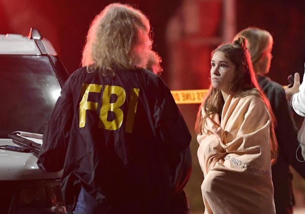 An FBI agent talks to a potential witness Nov. 8, 2018, as they stand near the scene in Thousand Oaks, California, where a gunman opened fire inside a country dance bar crowded with hundreds of people on "college night." 