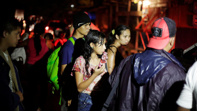 Hondurans, part of a new caravan of migrants travelling towards the United States, are seen as they wait to catch a ride in Cofradia 