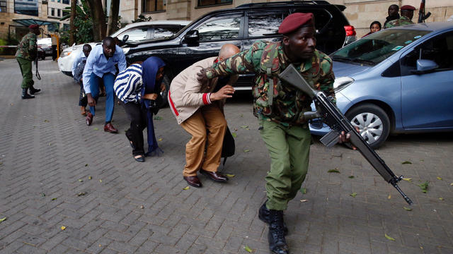 People are evacuated by a member of security forces at the scene where explosions and gunshots were heard at the Dusit hotel compound, in Nairobi 