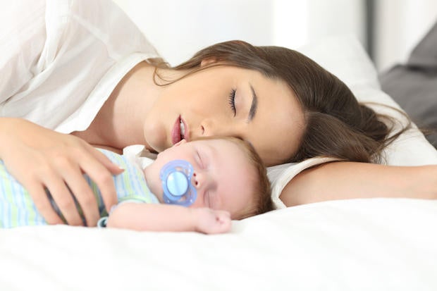 Tired mother sleeping with her baby 