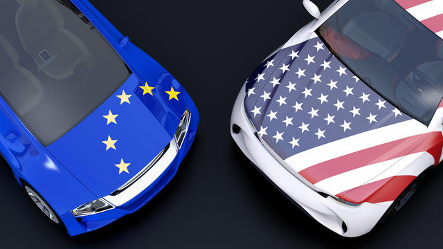 EU and US flags on two automobiles hood. black background 