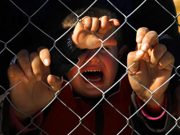 FILE PHOTO -  A Kurdish refugee child cries as he and others wait inside a fenced refugee camp to pay their last respects to a Kurdish fighter killed during the battle for Kobani against Islamic State, in Suruc 