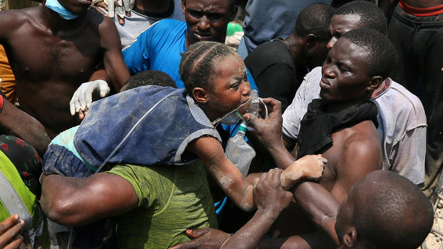 Men carry a boy who was rescued at the site of a collapsed building containing a school in Nigeria's commercial capital of Lagos 