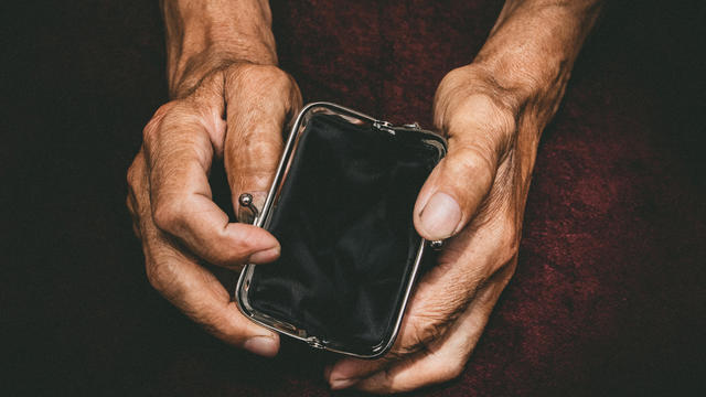 Elderly man holds in his hands an empty wallet. Vintage empty purse in wrinkled hands . Poverty in retirement concept. Special toning 