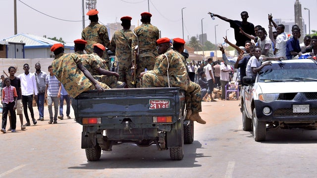 Sudanese demonstrators cheer as they drive towards a military vehicle near Defence Ministry in Khartoum 