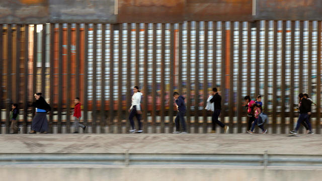Migrants from Central America walk along the border fence after crossing the Rio Bravo to illegally enter El Paso, Texas, U.S. to request asylum, as seen from Ciudad Juarez 