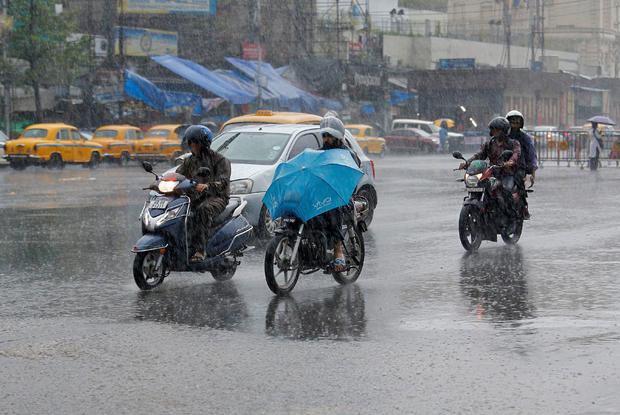 People ride their motorbikes during heavy rains in Kolkata 