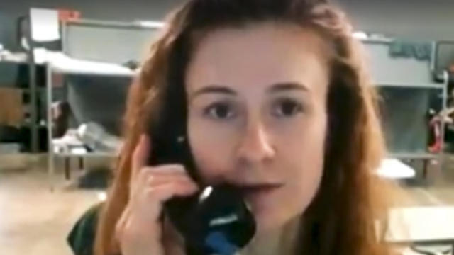 In this image taken from video, Maria Butina speaks on a phone in a dormitory with bunk beds in Chickasha, Oklahoma. 