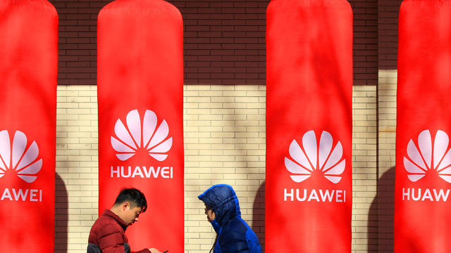 People walk past logos of Huawei in Huaian 