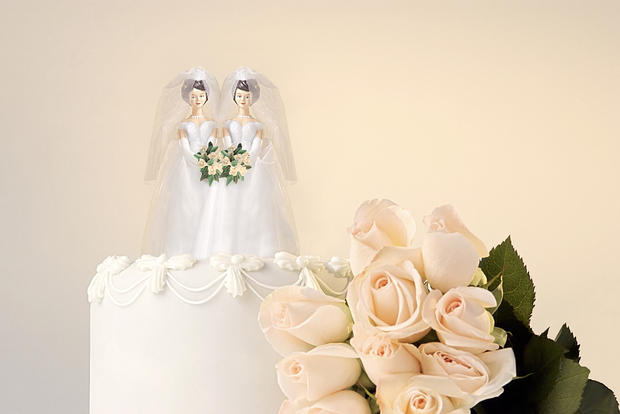 Still life of the top of a wedding cake with two miniature brides cake topper and roses at the side 