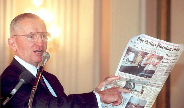 Ross Perot holds up a newspaper 