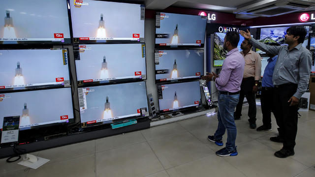 People celebrate as they watch a live broadcast of India's second lunar mission, Chandrayaan-2, inside an electronics showroom in Kolkata 