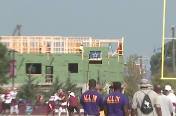Construction workers put up a Dallas Cowboy flag within sight of players at Redskins training camp 