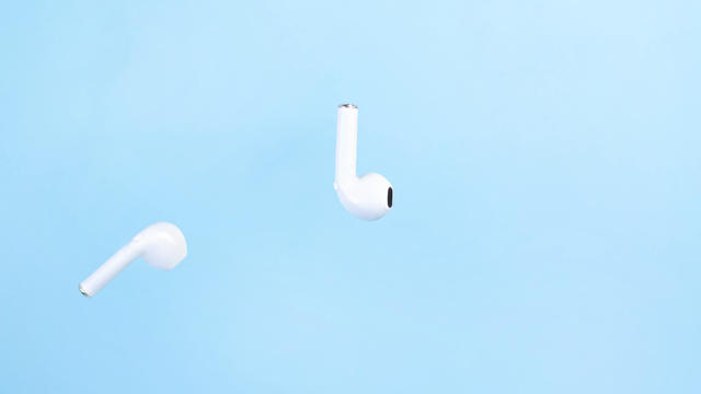 Cordless white headphones in the air on a blue background. 
