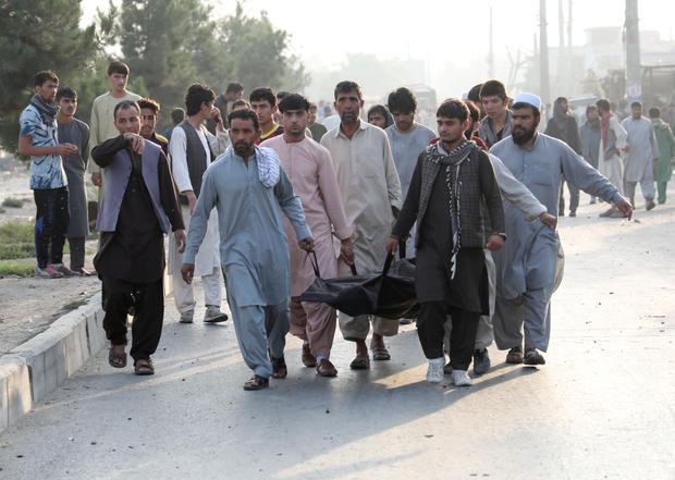 Afghan men carry the dead body of a civilian at the site of a blast in Kabul 