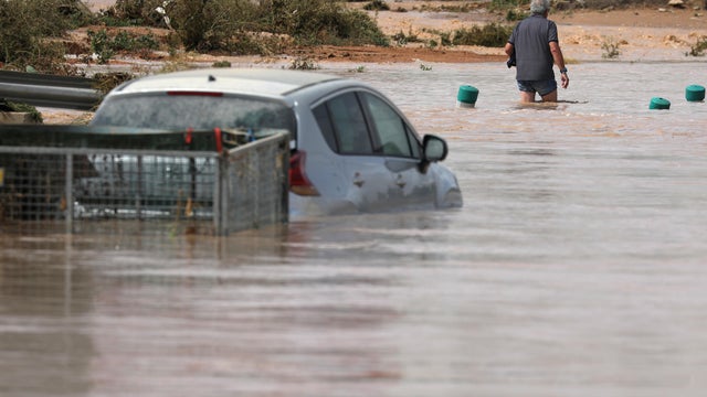 A man wades through a flooded street after heavy rains in San Javier 