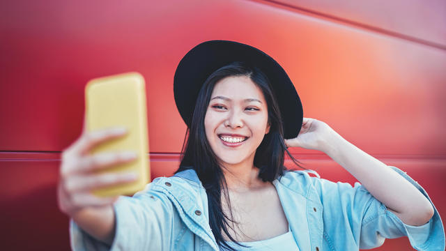 Happy Asian girl doing a video story with mobile smart phone outdoor - Chinese woman web influence having fun with new trends social networks app - People, millennial generation and technology concept 
