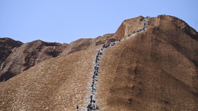 Tourists climb Uluru, formerly known as Ayers Rock, at Uluru-Kata Tjuta National Park in the Northern Territory 