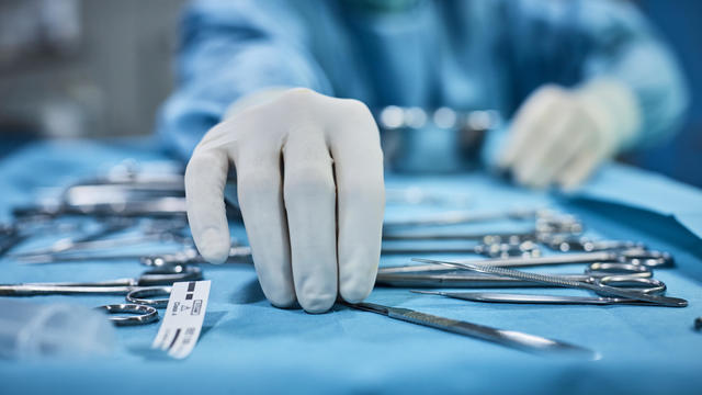 Surgeon picking up surgical tool from tray 