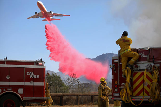 Cal Fire firefighters look on as a plane drops fire retardant on the Maria Fire in Santa Paula, California, November 1, 2019. 