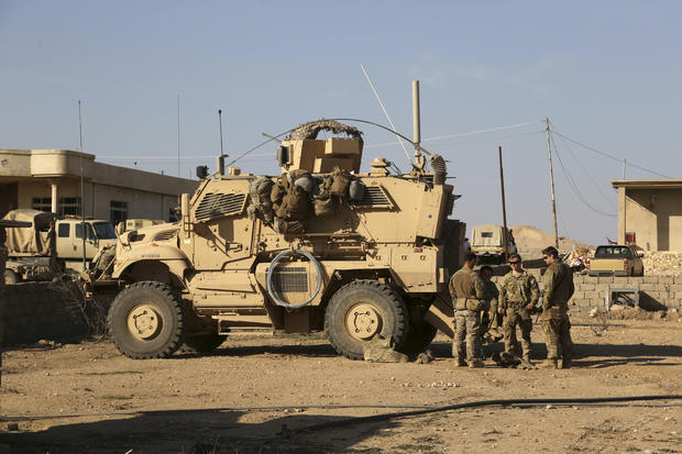 U.S. Army soldiers stand outside their armored vehicle on a joint base with the Iraqi army south of Mosul, Iraq, on February 23, 2017. 