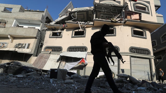Palestinian militant walks past the home of Islamic Jihad field commander Baha Abu Al-Atta after it was hit by an Israeli strike that killed him in Gaza City 