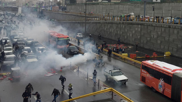 Riot police tries to disperse people as they protest on a highway against increased gas price in Tehran 