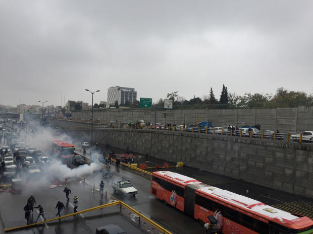 Riot police tries to disperse people as they protest on a highway against increased gas price in Tehran 