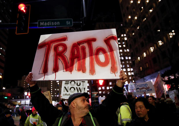 A man holds a sign reading "traitor" as protesters take part in a rally to support the impeachment and removal of President Trump in Seattle 