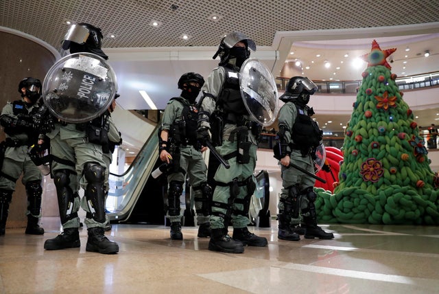 Riot police stand guard next to a Christmas tree inside a shopping mall during an anti-government protest on Christmas Eve at Tsim Sha Tsui in Hong Kong 