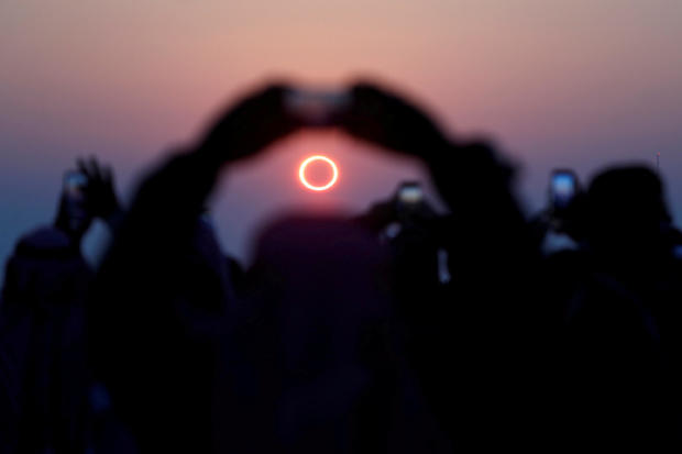 People take photos with their smartphones as they monitor the annular solar eclipse on Jabal Arba (Four Mountains) in Hofuf 