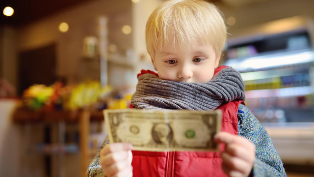 Little boy holds a one-dollar currency note. 