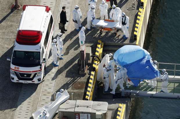 Officers in protective gear escort a person who was on board cruise ship Diamond Princess and was tested positive for coronavirus, after the person is transferred to a maritime police base in Yokohama 