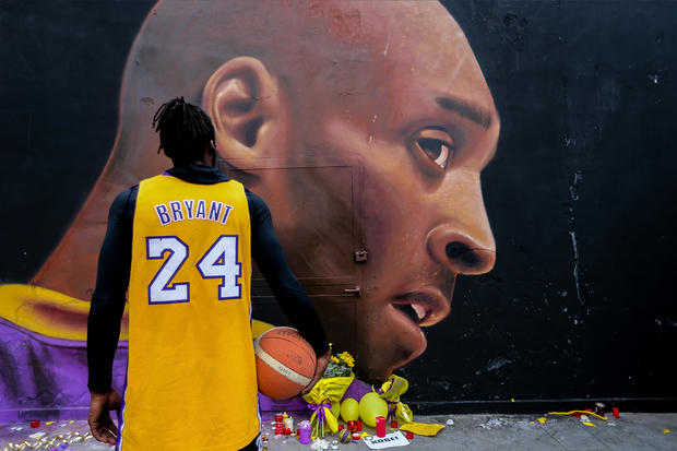 A boy in Kobe Bryant's shirt looks at the mural by Jorit 