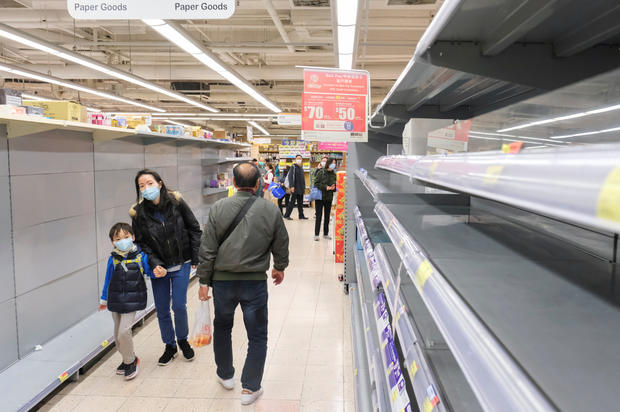 Customers wear masks as they walk past empty toilet paper shelves at a supermarket, following the outbreak of a new coronavirus, in Hong Kong 