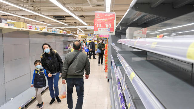 Customers wear masks as they walk past empty toilet paper shelves at a supermarket, following the outbreak of a new coronavirus, in Hong Kong 