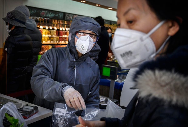 A Chinese worker wears a protective suit and mask as she scans groceries for a customer at a supermarket on February 11, 2020, in Beijing, China.