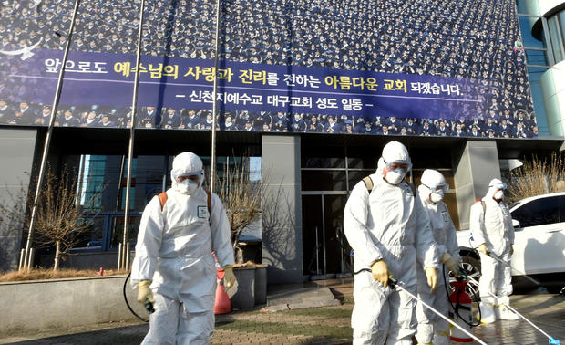 Workers from a disinfection service company sanitize a street in front of a branch of the Shincheonji Church of Jesus the Temple of the Tabernacle of the Testimony where a woman known as "Patient 31" attended a service in Daegu 