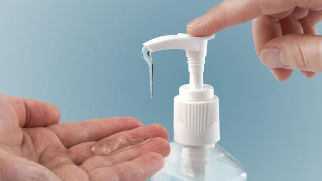 Photograph of a finger pumping sanitizer onto hand 