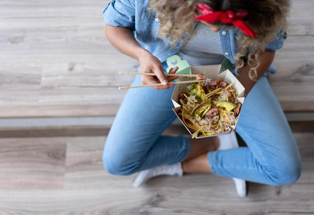 Woman eating a poke bowl at home while moving house 