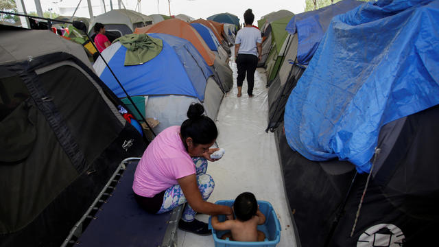 A migrant woman bathes her son outside their tent at a migrant encampment, where more than 2,000 people live while seeking asylum in the U.S, as the spread of the coronavirus disease (COVID-19) continues, in Matamoros 