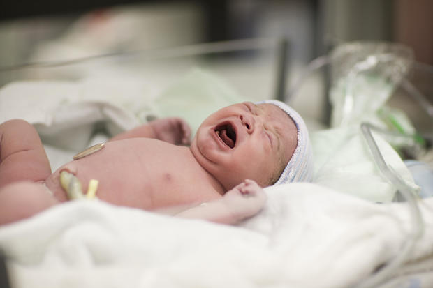 Newborn baby girl crying in hospital bassinet 