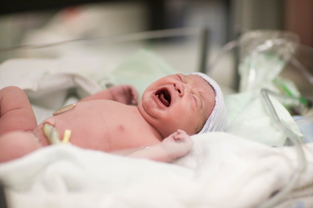Newborn baby girl crying in hospital bassinet 