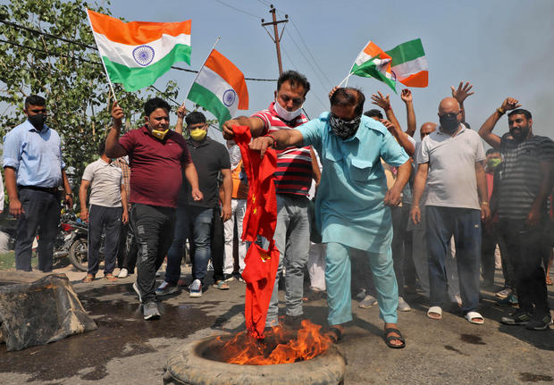 Demonstrators burn a flag resembling Chinese national flag during a protest against China, in Jammu 