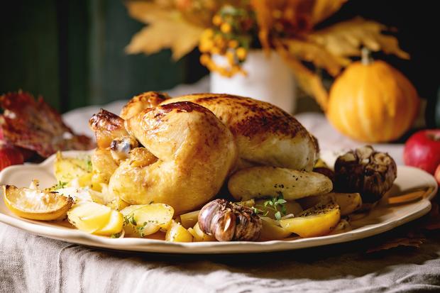 Thanksgiving or Halloween dinner with baked chicken with potatoes and lemons on big ceramic dish 