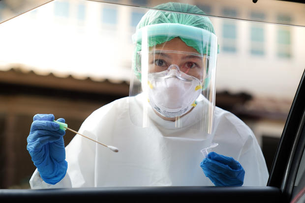 coronavirus COVID-19 test Portrait Of Doctor Wearing Protective Workwear Holding Medical Equipment Seen Through Car Window 