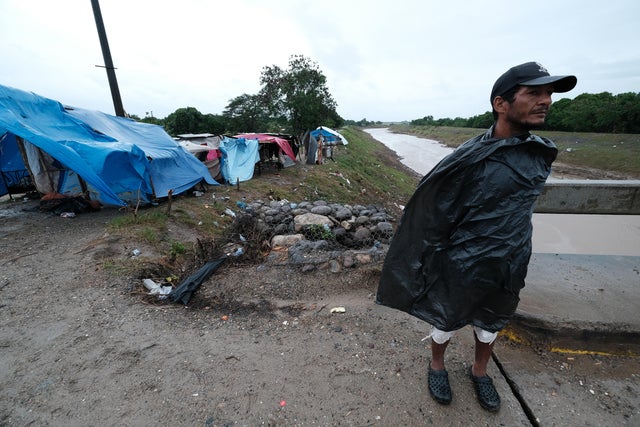 A man uses a plastic bag for protection from the rain as he surveils an area of Barrio San Juan where evacuated families live in shelters ahead of Tropical Storm Iota on November 17, 2020, in La Lima, Honduras. 