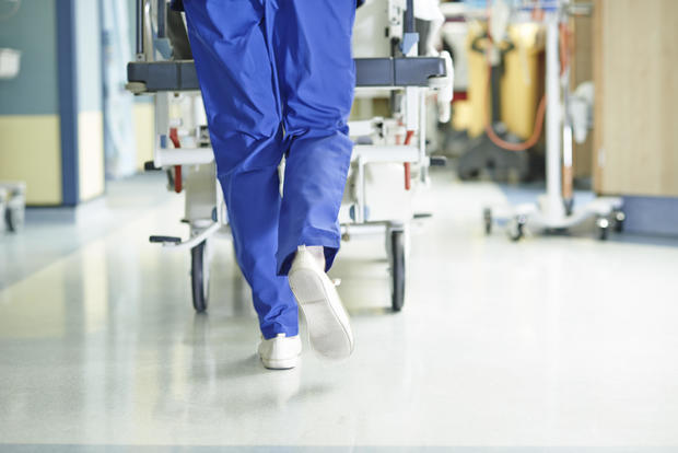 Legs of medic running with gurney along hospital corridor 